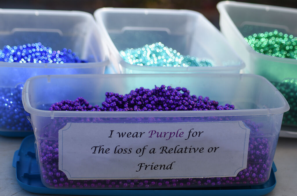 A tub of purple beads meant to represent the loss of a relative or friend sits on a table